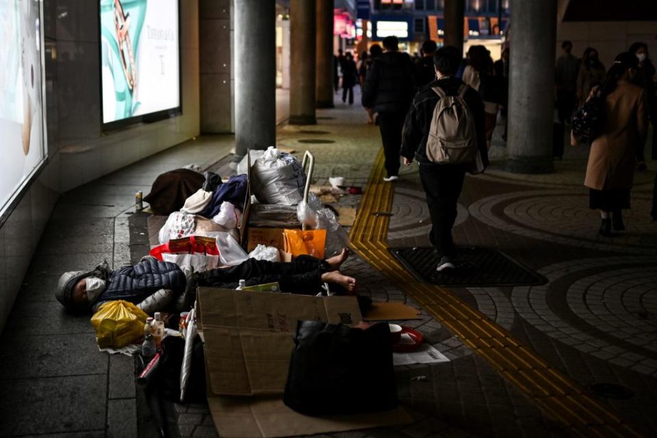 A homeless man sleeps on the pavement near Shinjuku station in Tokyo on November 18, 2020.<span class="copyright">CHARLY TRIBALLEAU/AFP via Getty Images</span>