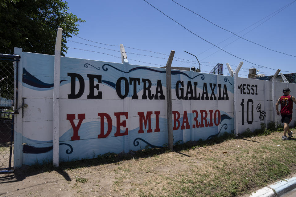 A man walks next to a mural that reads in Spanish: "From another galaxy and from my neighborhood," on the street where Lionel Messi lived in the Las Heras neighborhood of Rosario, Argentina, Wednesday, Dec. 14, 2022. (AP Photo/Rodrigo Abd)