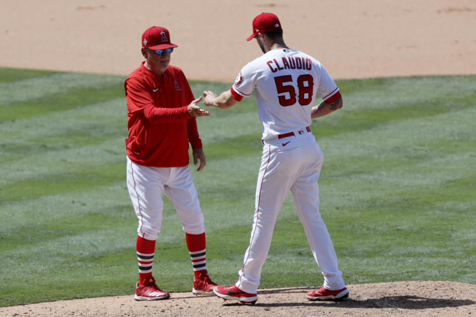 Los Angeles Angels manager Joe Maddon, left, removes relief pitcher Alex Claudio during the seventh inning of a baseball game against the Seattle Mariners in Anaheim, Calif., Sunday, June 6, 2021. (AP Photo/Alex Gallardo)