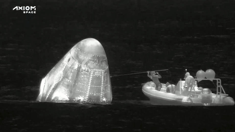 In this image from infrared video provided by SpaceX, recovery personnel approach the Dragon space capsule after splashdown in the Atlantic Ocean off the Florida coast on Monday, April 25, 2022. Three rich businessmen returned from the International Space Station with their astronaut escort, wrapping up a pricey trip that marked NASA’s debut as a B&B host. (SpaceX via AP)