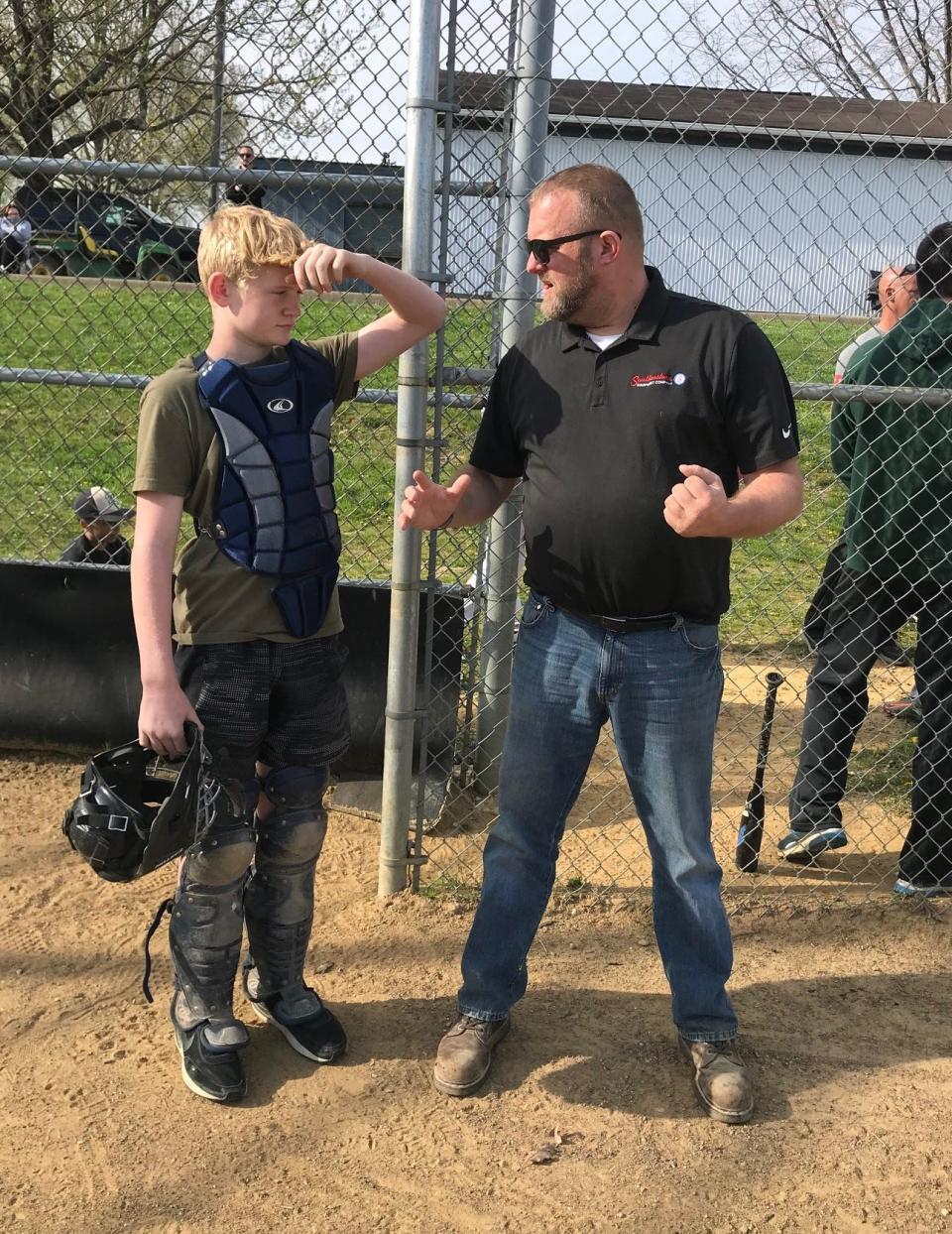 Cambridge Little League president Travis Daugherty talks to a young umpire as he prepares to call his first game.  The Cambridge Little League will hold its Opening Day Celebration on Saturday.