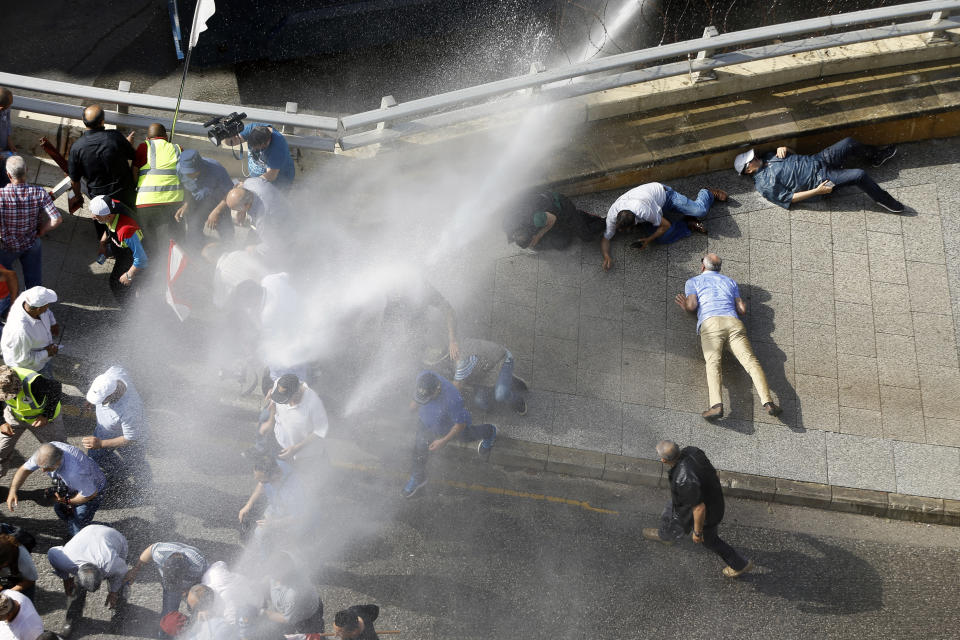 Retired Lebanese soldiers lay on the ground as police using water cannons during a protest in Beirut, Lebanon, Monday, May 20, 2019, as the government faces a looming fiscal crisis. Over one hundred protesters gathered Monday outside the Government House in downtown Beirut shouting "Thieves, thieves!" as the Cabinet met for its 16th session to reach agreement on controversial budget cuts. (AP Photo/Bilal Hussein)