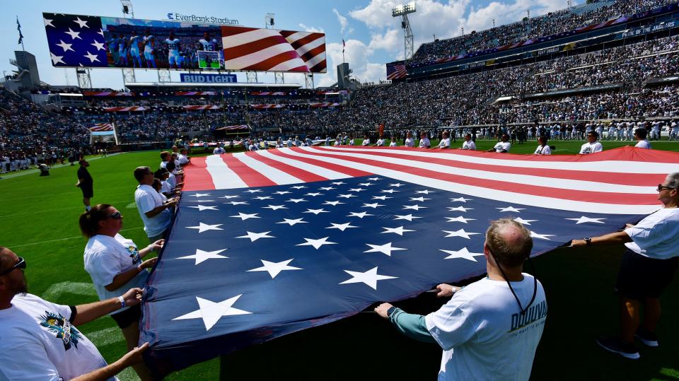 Jaguars season-ticket holders hold the American flag on the field before the game against Houston on Sept. 24.