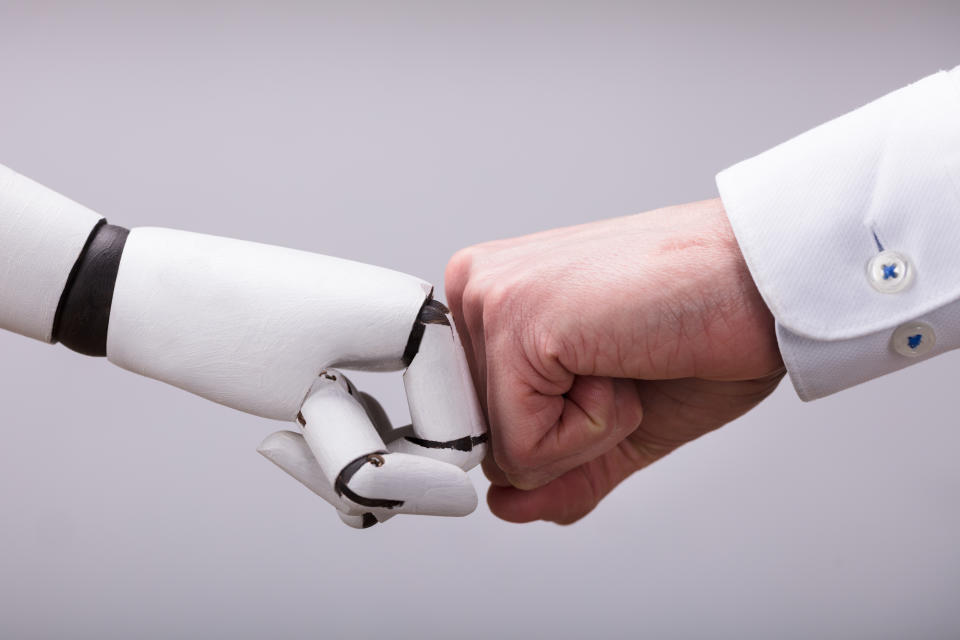 Robot And Human Hand Making Fist Bump On Grey Background