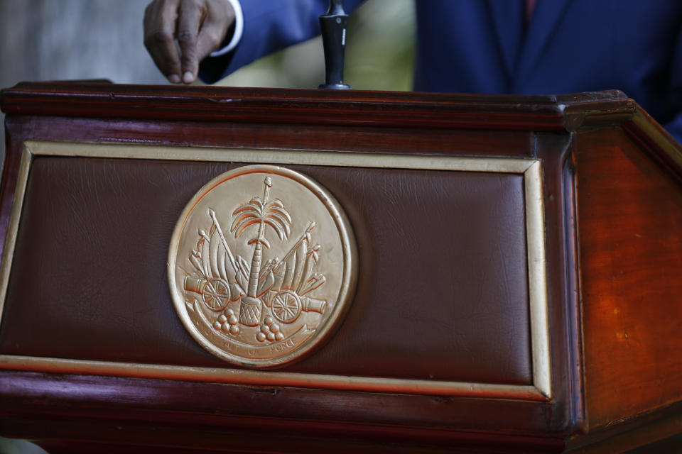 President Jovenel Moïse makes a point by tapping the podium, which is embossed with the national seal, reading in French, "Unity is strength," during a press conference at the National Palace in Port-au-Prince, Haiti, Tuesday, Oct. 15, 2019. Haiti's embattled president faced a fifth week of protests as road blocks and marches continue across the country, after opposition leaders said they will not back down on their call for Moïse to resign. (AP Photo/Rebecca Blackwell)