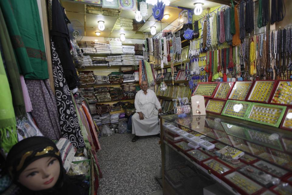 In this photo taken in Tuesday, Oct. 30, 2012, shop owner, Yousif Jassim Mohammed waits for customers in Najaf, Iraq. The plunge in Iran's currency is proving bad for business in neighboring Iraq. Fewer Iranians are now able to afford visits to Shiite holy sites here and elsewhere in Iraq because each dollar or Iraqi dinar now costs roughly three times what it did as recently as last year. That has pushed the price of organized tours up sharply and made Iraqi merchants far less willing to accept rials as payment. (AP Photo/Khalid Mohammed)