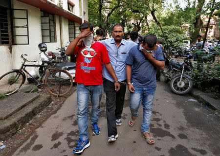 A policeman escorts men who they said were arrested on Wednesday on suspicion of tricking American citizens into sending them money by posing as U.S. tax officials, at a court in Thane, on the outskirts of Mumbai, India, October 6, 2016. REUTERS/Danish Siddiqui/File Photo