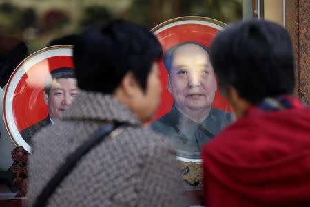 Tourists look at souvenir plates with images of late Chairman Mao Zedong (R) and President Xi Jinping outside a shop next to Tiananmen Square. REUTERS/Jason Lee