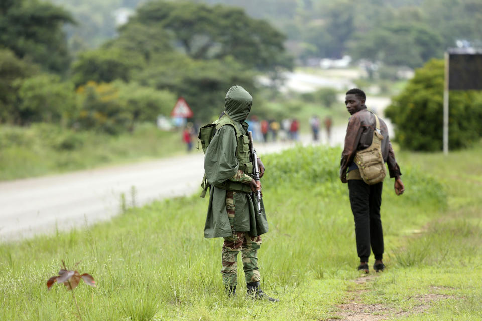 A soldier patrols as protestors gather during a demonstration over the hike in fuel prices in Harare, Zimbabwe, Tuesday, Jan. 15, 2019. A Zimbabwean military helicopter on Tuesday fired tear gas at demonstrators blocking a road and burning tires in the capital on a second day of deadly protests after the government more than doubled the price of fuel in the economically shattered country. (AP Photo/Tsvangirayi Mukwazhi)