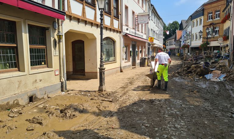 Un hombre despeja escombros con una carretilla a través de las calles del pueblo afectado por la inundación Ahrweiler, Alemania.
