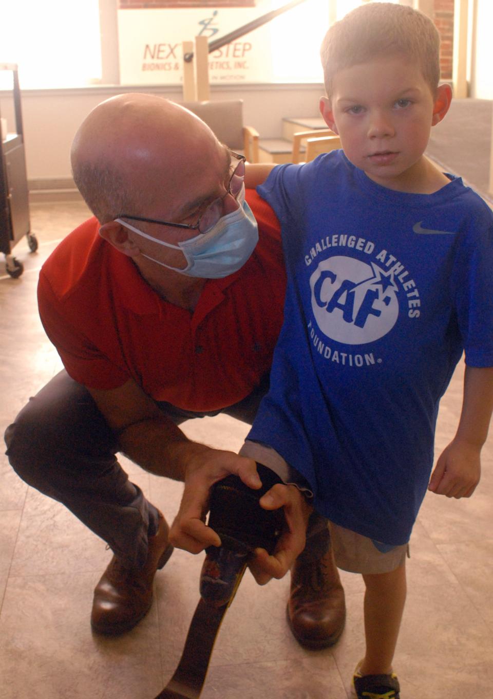 Scott Cummings, a certified prosthetist at Next Step Bionics in Manchester, New Hampshire, lifts a piece of 3-year-old TJ DeAngelo's personalized prosthesis to show an image of Lighting McQueen from Pixar's "Cars."