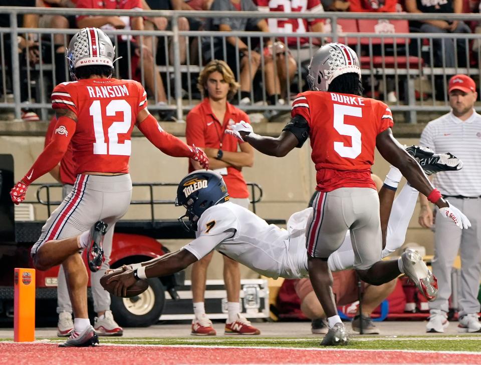 Sep 17, 2022; Columbus, Ohio, USA; Toledo Rockets quarterback Dequan Finn (7) leaps into the end zone for a touchdown as Ohio State Buckeyes safety Lathan Ransom (12) and Ohio State Buckeyes cornerback Denzel Burke (5) defend during Saturday's NCAA Division I football game at Ohio Stadium. Mandatory Credit: Barbara Perenic/Columbus Dispatch