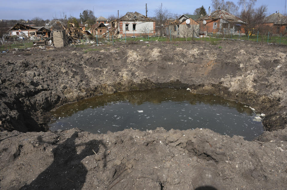 A crater from an explosion is seen next to apartment buildings damaged by shelling in the city of Chuhuiv, Kharkiv region, Ukraine, Friday, April 8, 2022. (AP Photo/Andrew Marienko)