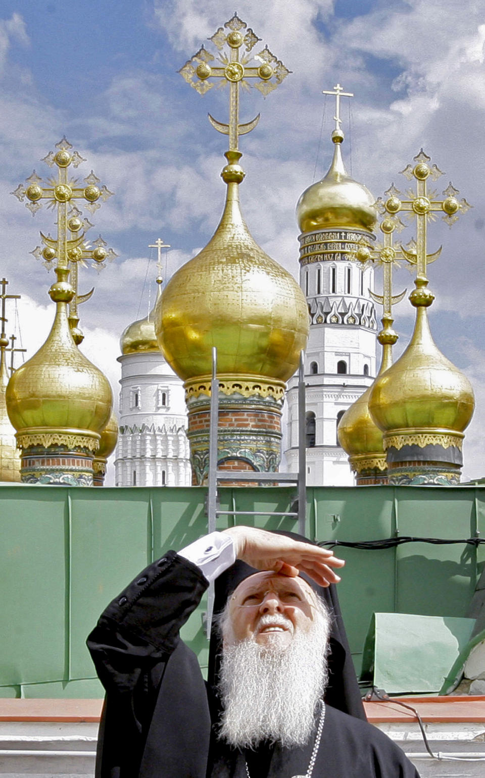 FILE - In this Tuesday, May 25, 2010 file photo, Ecumenical Patriarch Bartholomew I of Constantinople, shields his eyes from the sun as he stands on a roof overlooking the Kremlin in Moscow, Russia. Bartholomew claims the exclusive right to grant the “Tomos of Autocephaly,” or full ecclesiastic independence, sought by the Ukrainians. It would be a momentous step, splitting the world’s largest Eastern Orthodox denomination and dealing a body blow to the power and prestige of the Moscow Patriarchate, which has positioned itself as leading player within the global Orthodox community. (Dmitry Astakhov/Sputnik Government Pool Photo via AP, File)