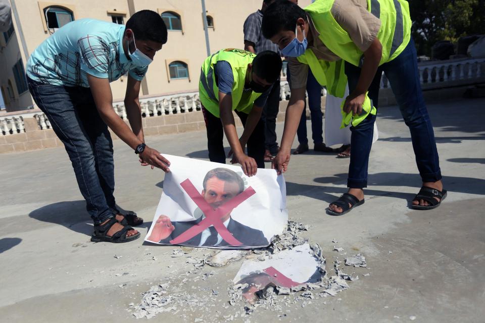 Palestinian demonstrators burn pictures of French President Emmanuel Macron during a rally to protest his comments over Prophet Mohammed cartoons, in Deir al-Balah in the central Gaza Strip, on October 25, 2020. (Photo by Majdi Fathi/NurPhoto via Getty Images)