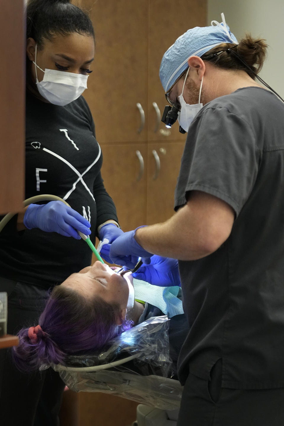 Dental assistant Jasmine Webb, left, and dentist Ryan O'Neill, right, repair the teeth of Danielle Wilkes during a clinic visit Thursday, Sept. 7, 2023, in Nashville, Tenn. Wilkes waited five years to have her teeth repaired after getting several teeth knocked out in a car wreck. She was able to receive dental care after an expansion of the state's Medicaid program. (AP Photo/George Walker IV)