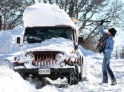 Nancy Campbell of Winchester, Va. uses a broom to clear snow from the roof of her Jeep Sunday, Jan. 24, 2016, after an historic winter storm dumped more than 30 inches of snow in the area. [Jeff Taylor/The Winchester Star via AP]