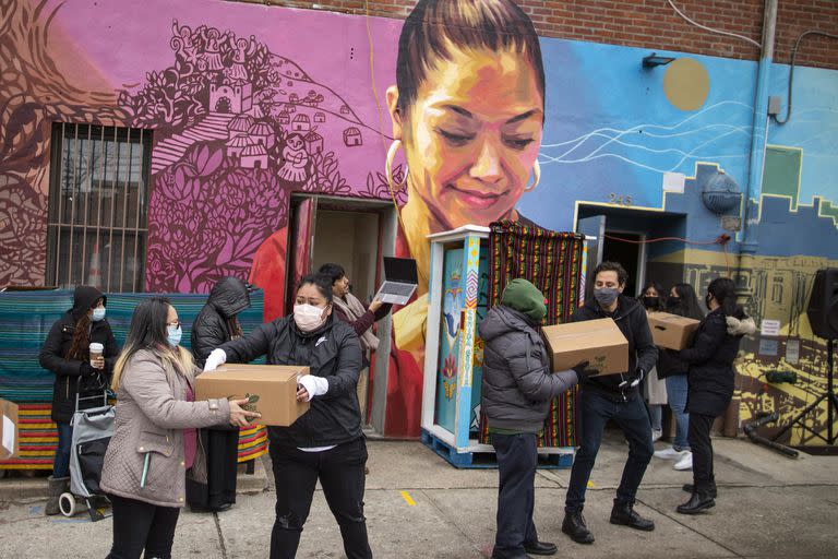 Voluntarios movilizan despensas de alimentos que serán donadas mientras vecinos del barrio reciben información sobre las vacunas contra el Covid en el centro comunitario Mixteca, Brooklyn