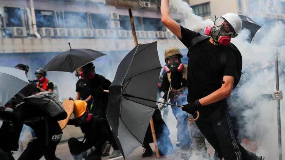 A demonstrator throws back a tear gas canister as they clash with riot police during a protest in Hong Kong in 2019