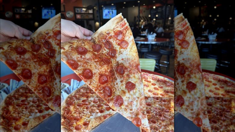 person holding large pizza slice