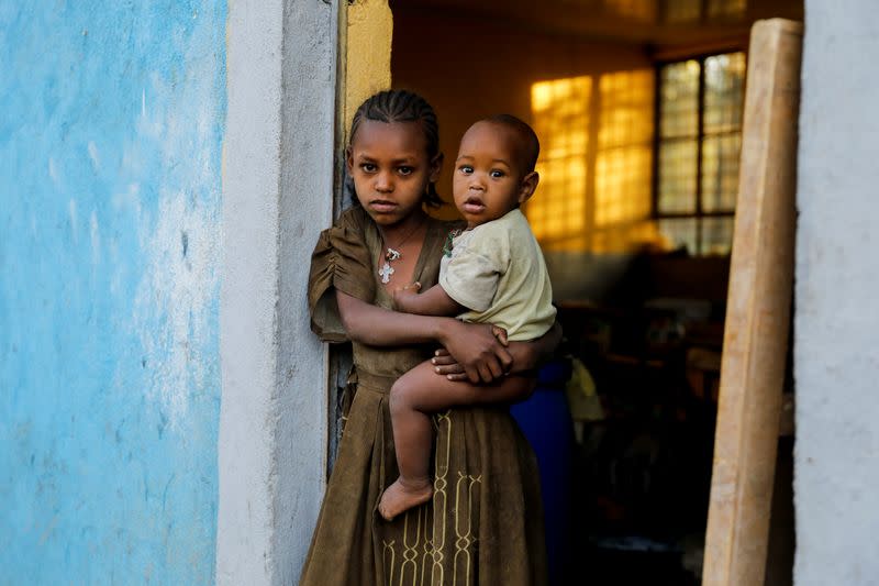 FILE PHOTO: An 11-year-old girl holds her one-year-old brother in the town of Shire in theTigray region of Ethiopia.