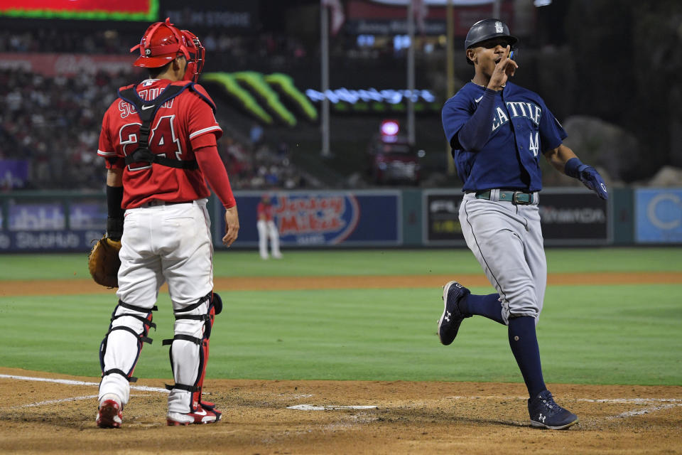 Seattle Mariners' Julio Rodriguez, right, celebrates after he scored on a single by Kevin Padlo as Los Angeles Angels catcher Kurt Suzuki stands at the plate during the sixth inning of a baseball game Saturday, June 25, 2022, in Anaheim, Calif. (AP Photo/Mark J. Terrill)