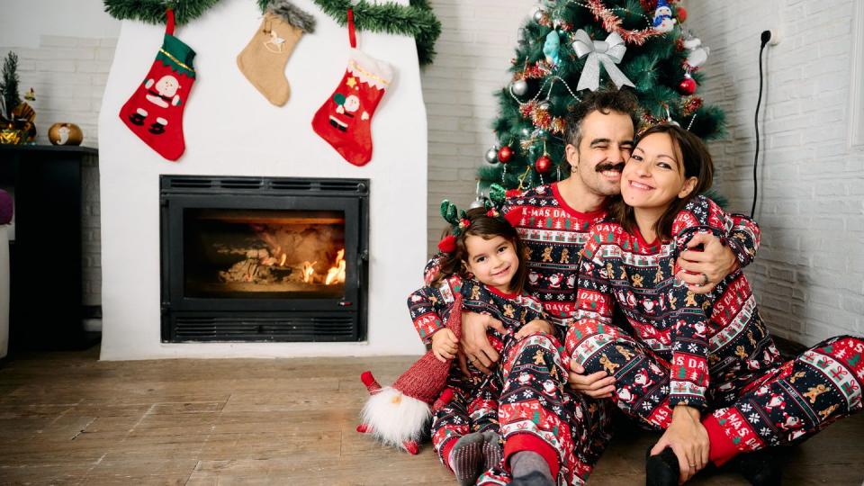 a family, with the father, mother, and daughter, wearing matching christmas pajamas, taking family photos in front of the fireplace and a christmas tree the scene represents the joy, love, and togetherness of the holiday season