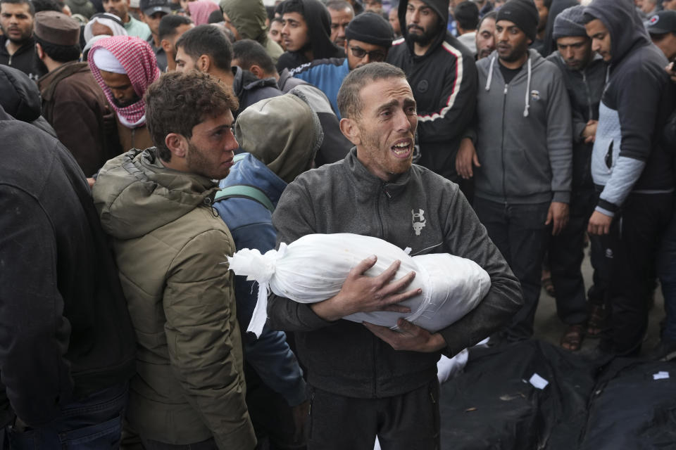 A Palestinian holds the body of a child killed in the Israeli bombardments of the Gaza Strip in front of the morgue to pray over them at Al Aqsa Hospital in Deir al Balah on Friday, Feb. 23, 2024. (AP Photo/Adel Hana)