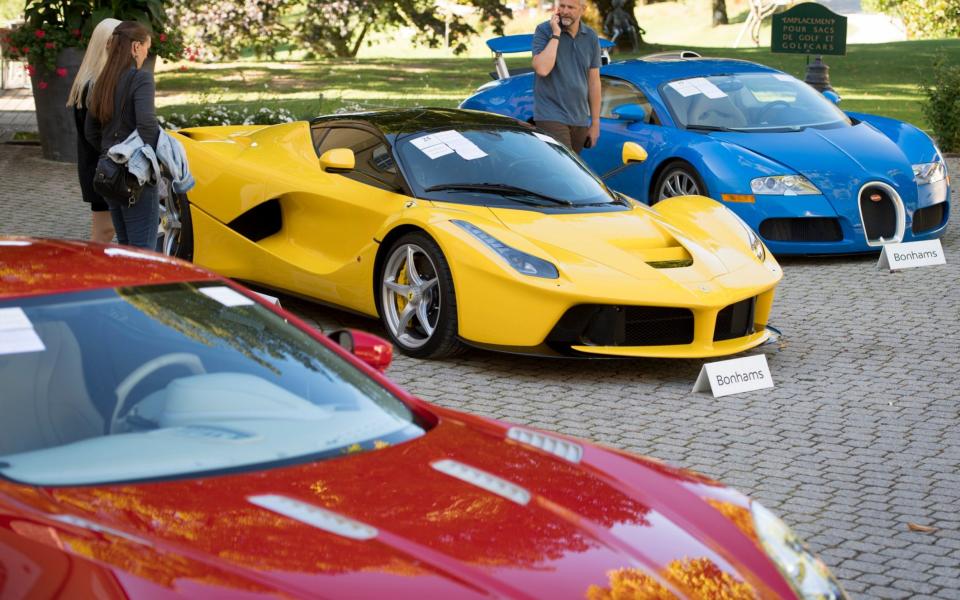 People looking at a Aston Martin One-77 Coupe (2011) in front of a Ferrari LaFerrari (2015), yellow, and a Bugatti Veyron EB 16.4 Coupe (2010), blue, part of some 25 luxury cars owned by Teodoro Obiang, the son of the Equatorial Guinea's President Teodoro Obiang Nguema Mbasogo - Laurent Gillieron/Keystone