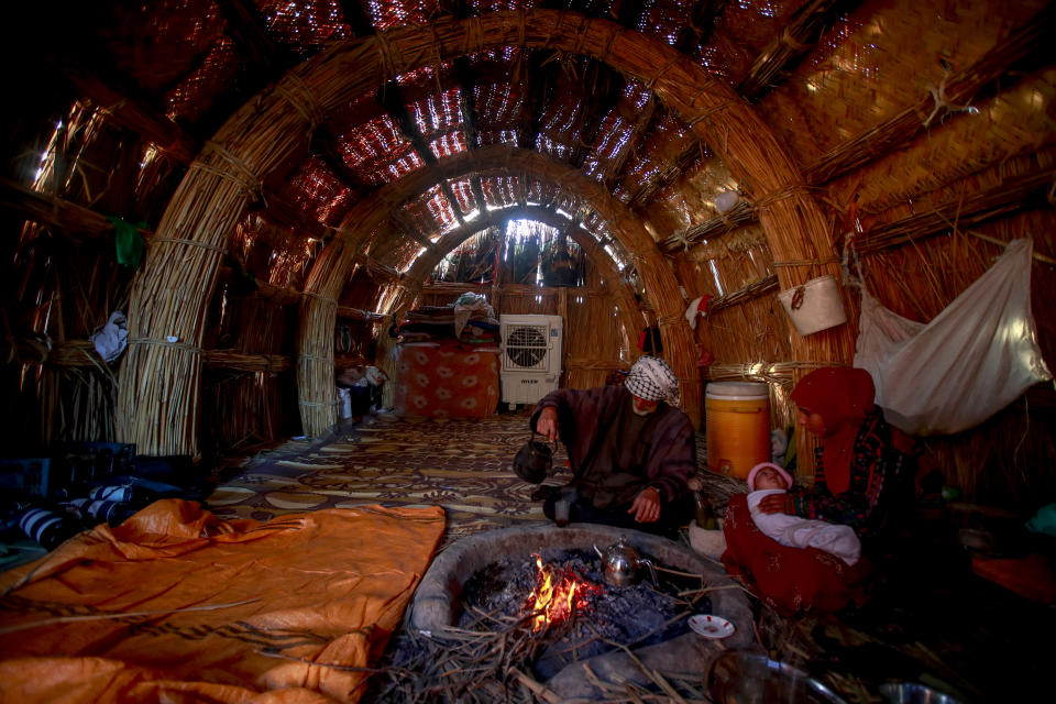 Razak Jabar makes tea inside his home in the marshes of Chibayish in Dhi Qar, Iraq, Sunday, Nov. 20, 2022. (AP Photo Anmar Khalil)