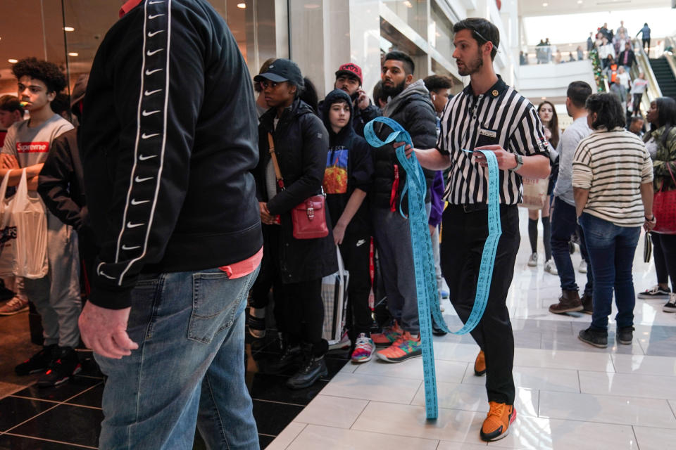 A Foot Locker employee hands out tickets to a line of people waiting for Kanye West's Yeezy shoes in King of Prussia mall on Black Friday, a day that kicks off the holiday shopping season, in King of Prussia, Pennsylvania, U.S., on November 29, 2019.  REUTERS/Sarah Silbiger