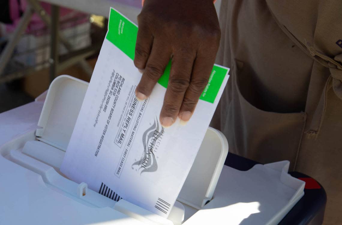 A poll worker places a mail-in absentee ballot in a secure box outside the Richland County Voter Registration office on Monday, Nov. 2, 2020.