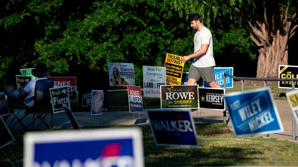 A person walks through campaign signs outside of the John Chavis Memorial Park Community Center polling site on Tuesday, May 17, 2022, in Raleigh, N.C.