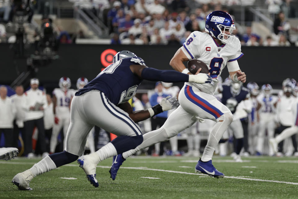 New York Giants quarterback Daniel Jones (8) runs the ball for a first down against Dallas Cowboys defensive end DeMarcus Lawrence (90) during the third quarter of an NFL football game, Monday, Sept. 26, 2022, in East Rutherford, N.J. (AP Photo/Adam Hunger)