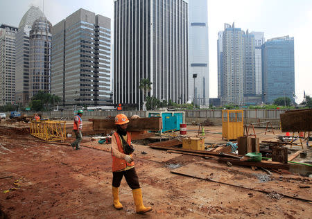 A worker carry pieces of wood as walks at the Jakarta Mass Rapid Transit construction at Sudirman Business District in Jakarta, Indonesia, April 17, 2018. REUTERS/Beawiharta