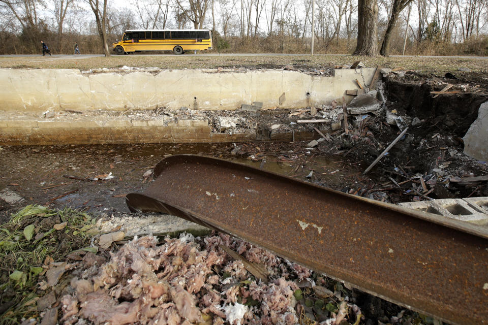 In this photo taken Monday, Nov. 18, 2019, a school bus drops students in front of a recently demolished home in Mosby, Mo. The home is one of dozens being torn down as part of a voluntary buyout program in the flood-prone town. (AP Photo/Charlie Riedel)