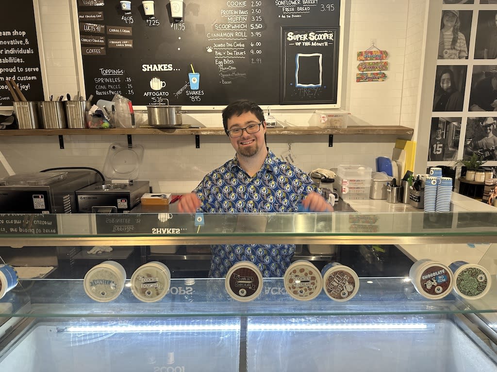 A man standing behind an ice cream counter and smiling