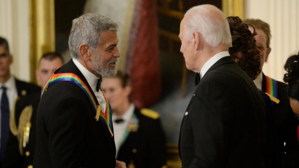 US President Joe Biden (R) greets George Clooney at a reception for Kennedy Center Honorees in the East Room of the White House