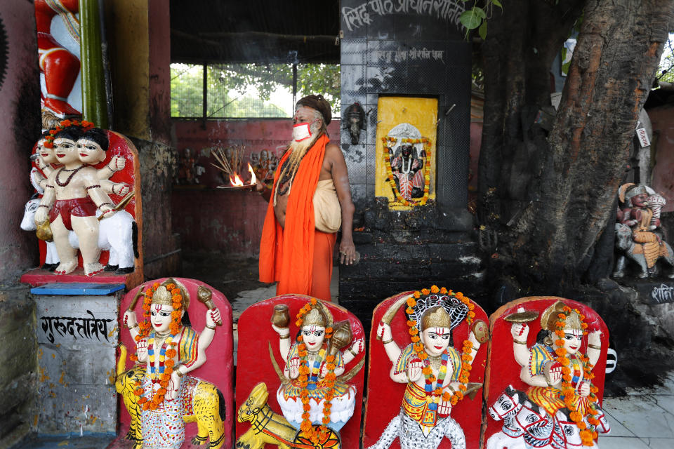 An Indian priest covers his face with a mask as a precaution against coronavirus prays at a temple, in Prayagraj, India, Monday, June 8, 2020. Religious places, malls, hotels and restaurants open Monday after more than two months of lockdown as a precaution against coronavirus. (AP Photo/Rajesh Kumar Singh)