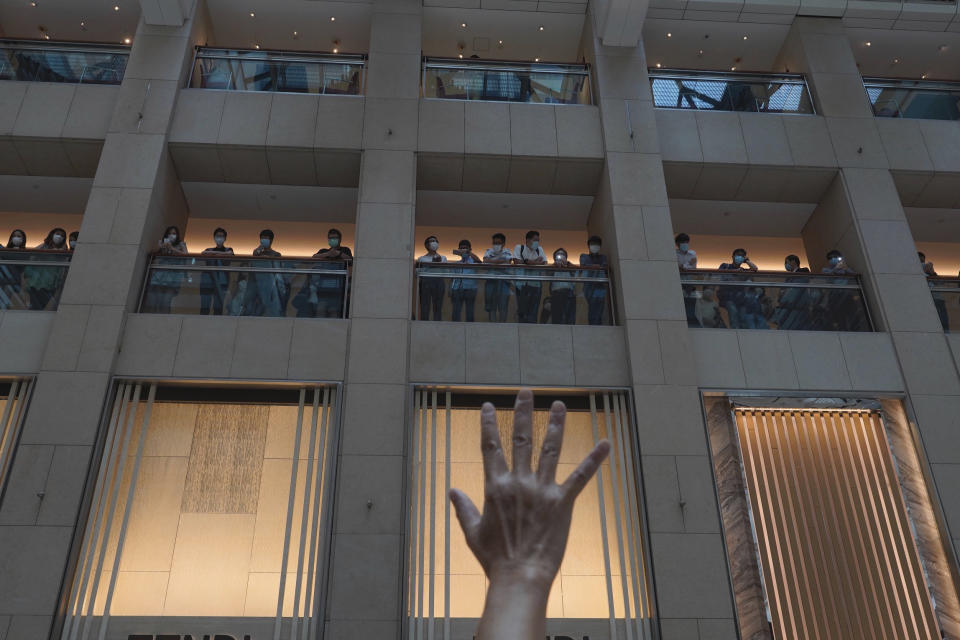 A protester gestures with five fingers, signifying the "Five demands - not one less" in a shopping mall during a protest against China's national security legislation for the city, in Hong Kong, Monday, June 1, 2020. The mouthpiece of China's ruling Communist Party says U.S. moves to end some trading privileges extended to Hong Kong grossly interfere in China's internal affairs and are doomed to fail. (AP Photo/Vincent Yu)