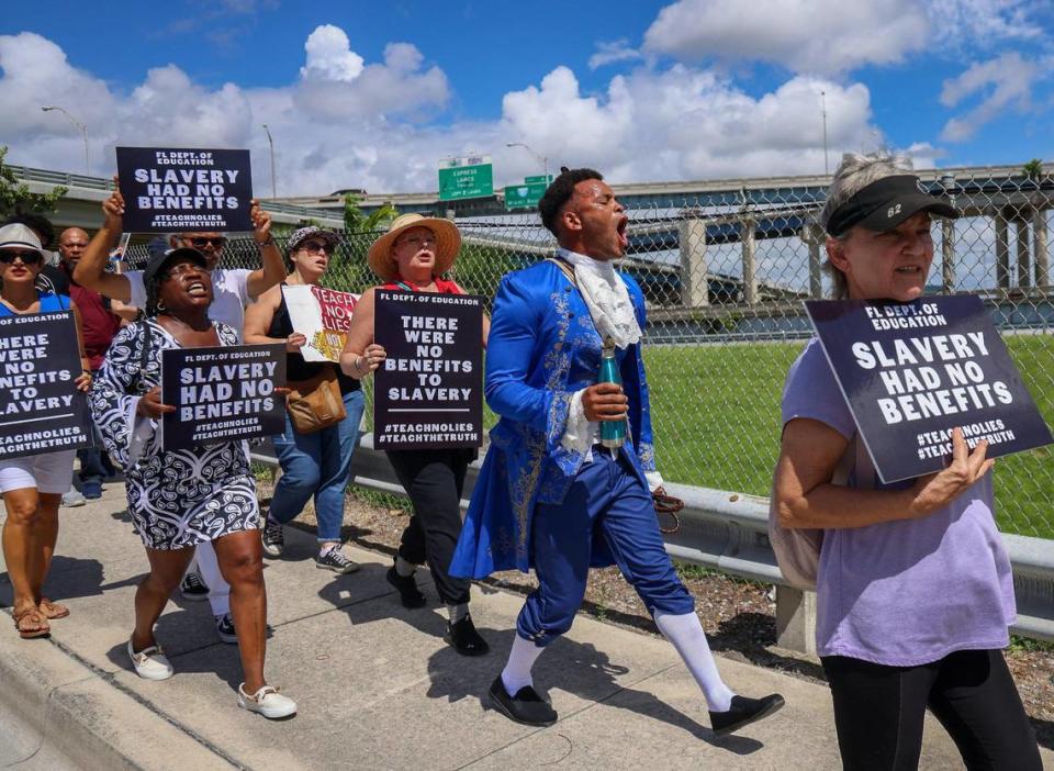 Jonathan Gartrelle, en el centro, dirige a un grupo de unos 80 manifestantes que entonan cánticos mientras marchan por el paso elevado de Northwest 14th Street después de salir de la Secundaria Booker T. Washington Sr.. Marcharon hacia el edificio de la Junta Escolar de Miami-Dade para protestar contra los nuevos estándares de historia afroamericana aprobados por el estado en julio, el miércoles 16 de agosto de 2023, en Miami, Florida.