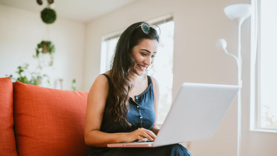 An Indian American woman works on a design project in the comfort of her apartment living room.