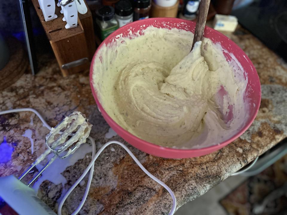 Mashed potatoes in a bowl next to hand mixer