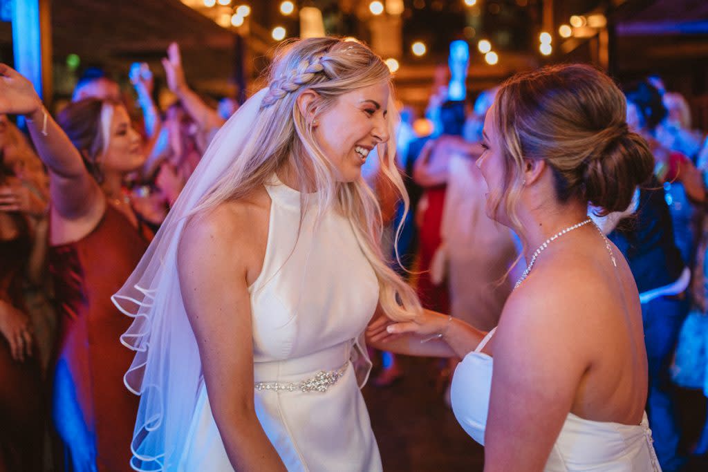 Two brides dance at their wedding reception. 