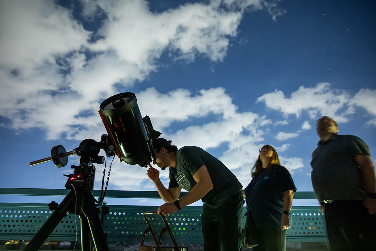 A young man looks through a telescope.