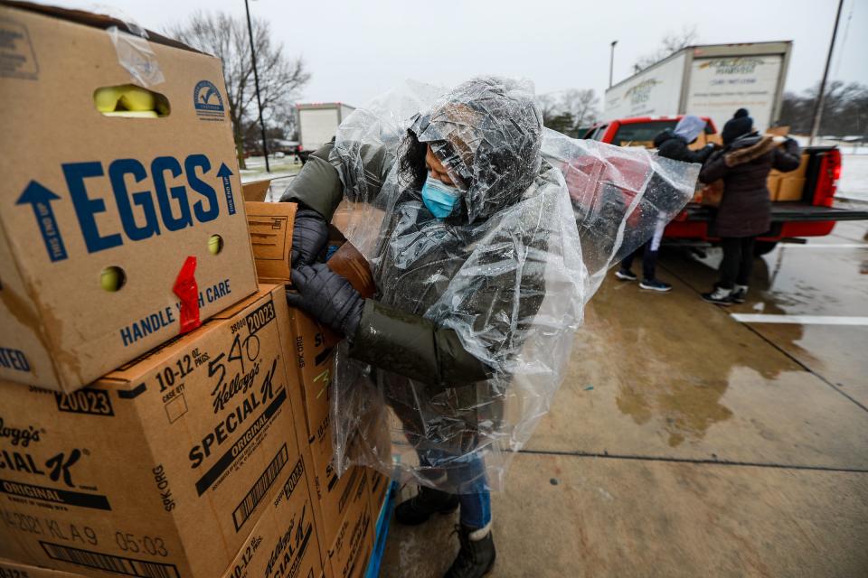 Amy Hennes, 57, of Ferndale, works to open boxes of food to hand out during the Forgotten Harvest Mobile Pantry at Oak Park recreation center in Oak Park on Dec. 30, 2020. Top 10 Cares partnered with Forgotten Harvest to hand out prepared meals made by restaurants affected by the COVID-19 pandemic.