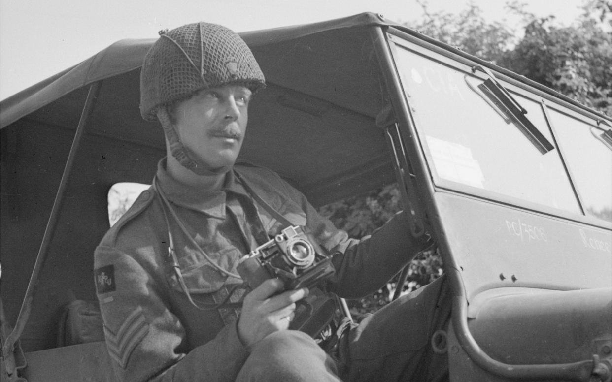 Army Film and Photographic Unit photographer Sgt Norman Midgley in his jeep, his official issue Super Ikonta camera at the ready during the assault on Caen, France, 1944. - AFPU/IWM