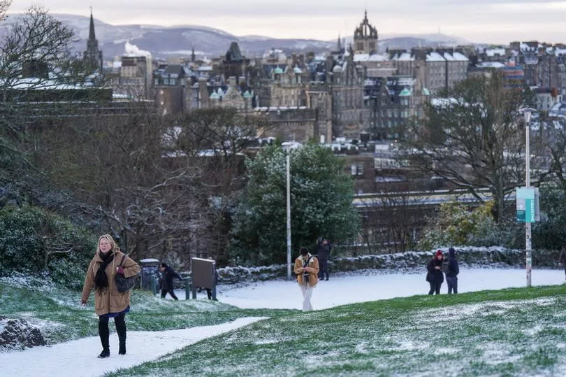 People are seen walking in the snow on Calton Hill.