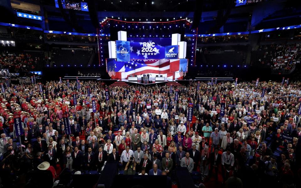 Delegates turn to pose for the official convention photographer at the end of the first session of the RNC