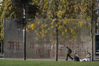 A man walks past graffiti referring to coronavirus, in Manchester city centre, England, Tuesday Oct. 20, 2020. The UK government has adopted a three-tier system for England, with areas classed as medium, high of very high risk. So far, only the Liverpool and Lancashire regions of northwest England have been placed in the highest tier. Nearby Greater Manchester, with a population of almost 3 million, has been holding out for more support for workers and businesses affected by the restrictions. (AP Photo/Jon Super)